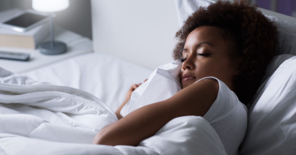 Young african woman sleeping in her bed at night, she is resting with eyes closed
