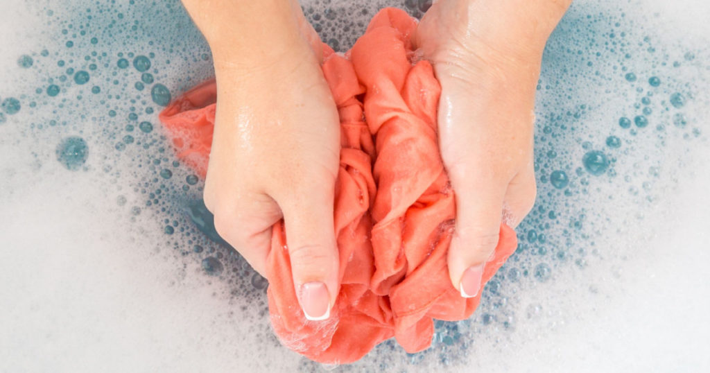 Female hands washing color clothes in sink
