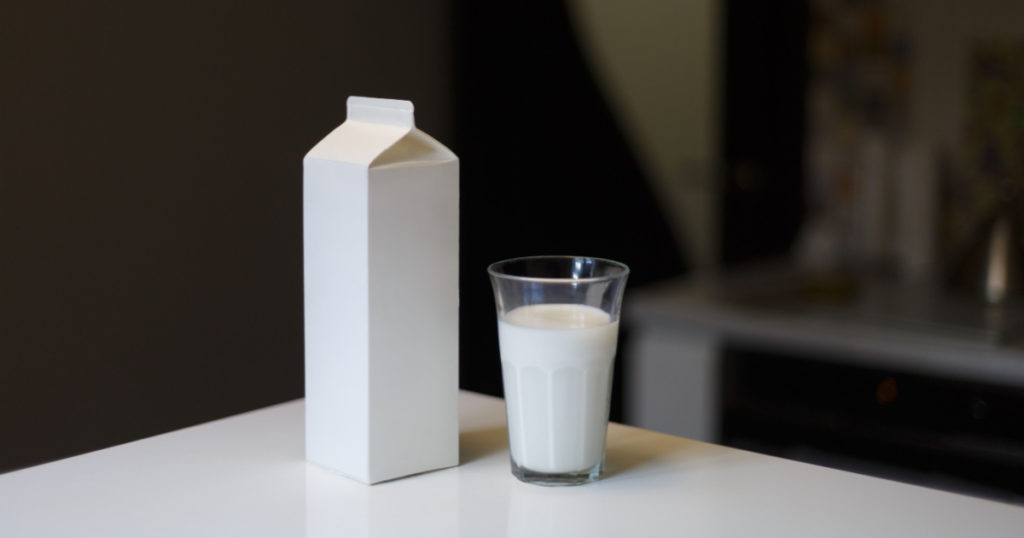 Carton box and glass of milk on table in kitchen
