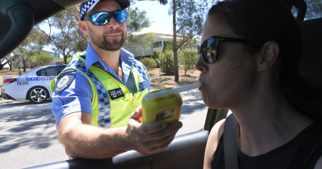 PERTH, WA - OCT 27 2019:Australian traffic police officer using breathalyzer on woman driver during field sobriety testing.Traffic accidents are predominantly caused by Impaired driving
