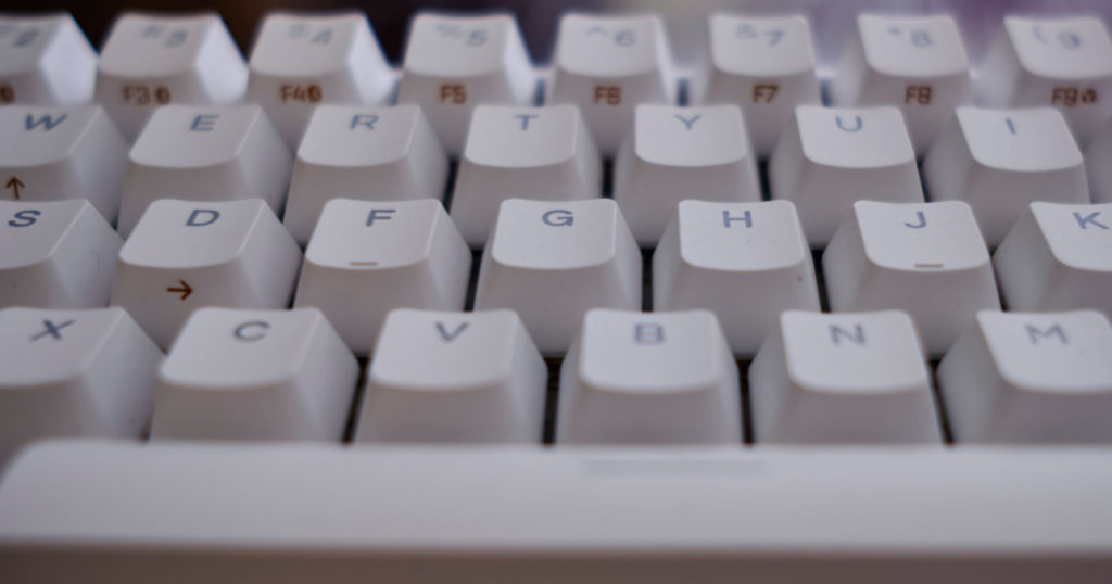 Close and front view of a white mechanical keyboard focused in keys D F G H J
