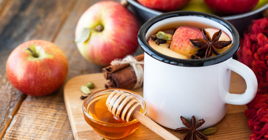 Homemade hot fruit tea with fresh apples, honey, spices: cinnamon, cardamon, anise, clove. Warm autumn drink, delicious healthy beverage.