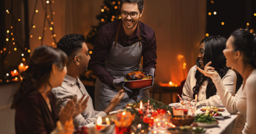 holidays and celebration concept - multiethnic group of happy friends having christmas dinner at home
