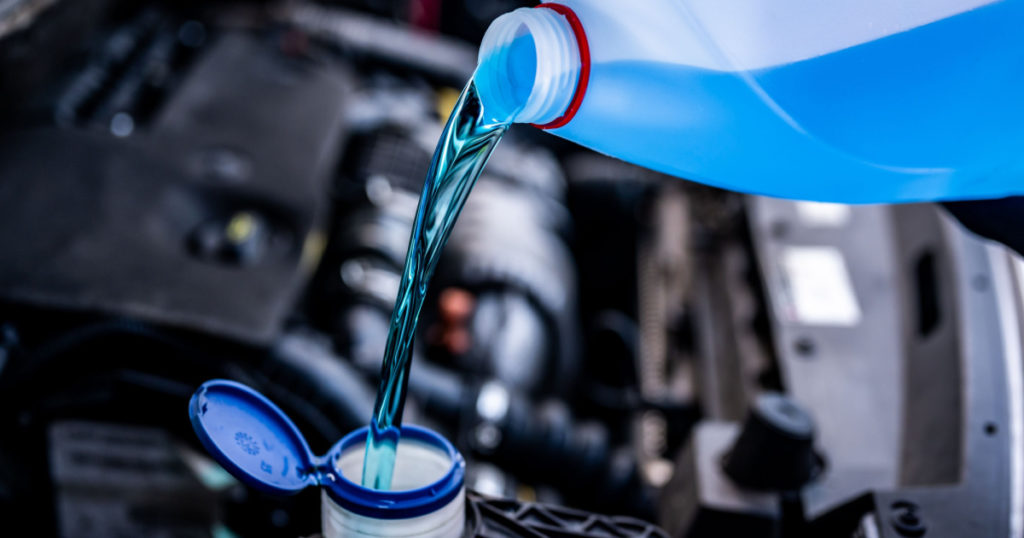 Pouring antifreeze. Filling a windshield washer tank with an antifreeze in winter cold weather.
