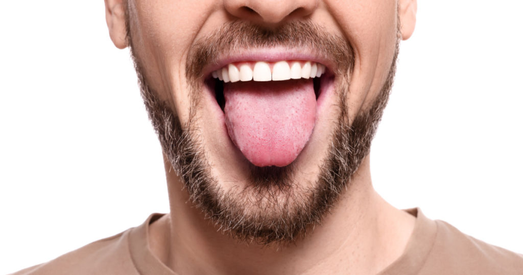 Happy man showing his tongue on white background, closeup
