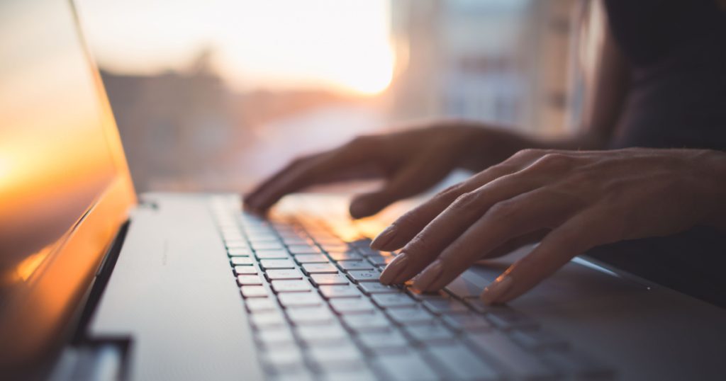 Woman working at home office hand on keyboard close up 