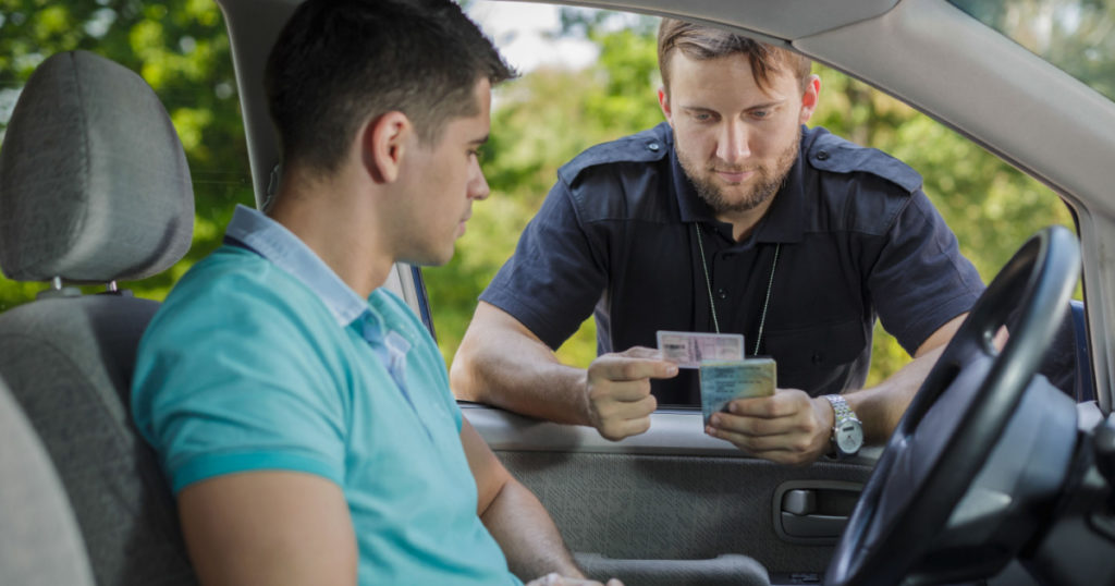 Experienced policeman is checking young man's driving licence
