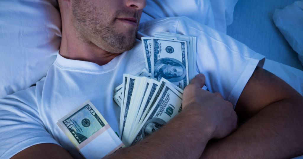 Man Sleeping On Bed With Bundle Of Currency Notes
