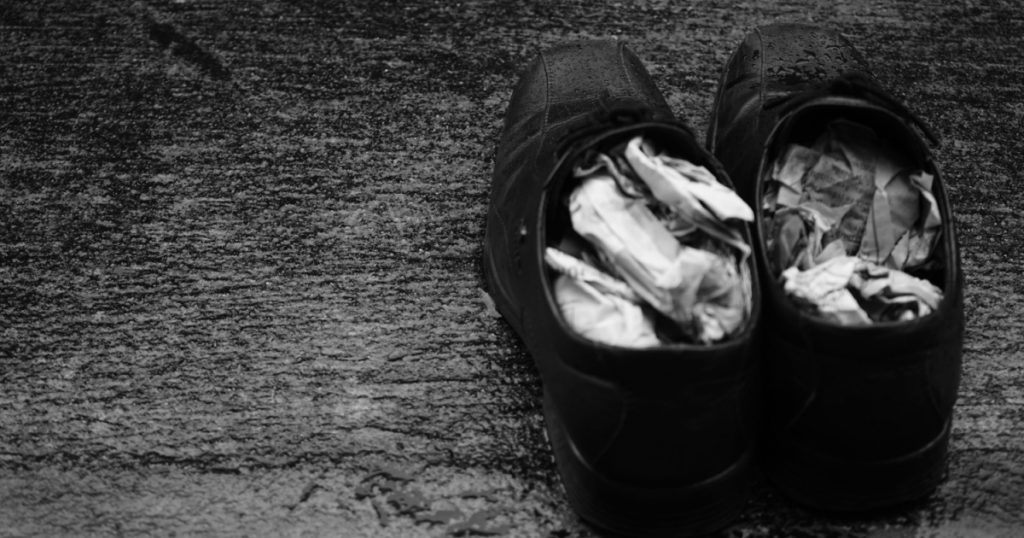 Wet shoes with folded newspaper inside in the rainy day

