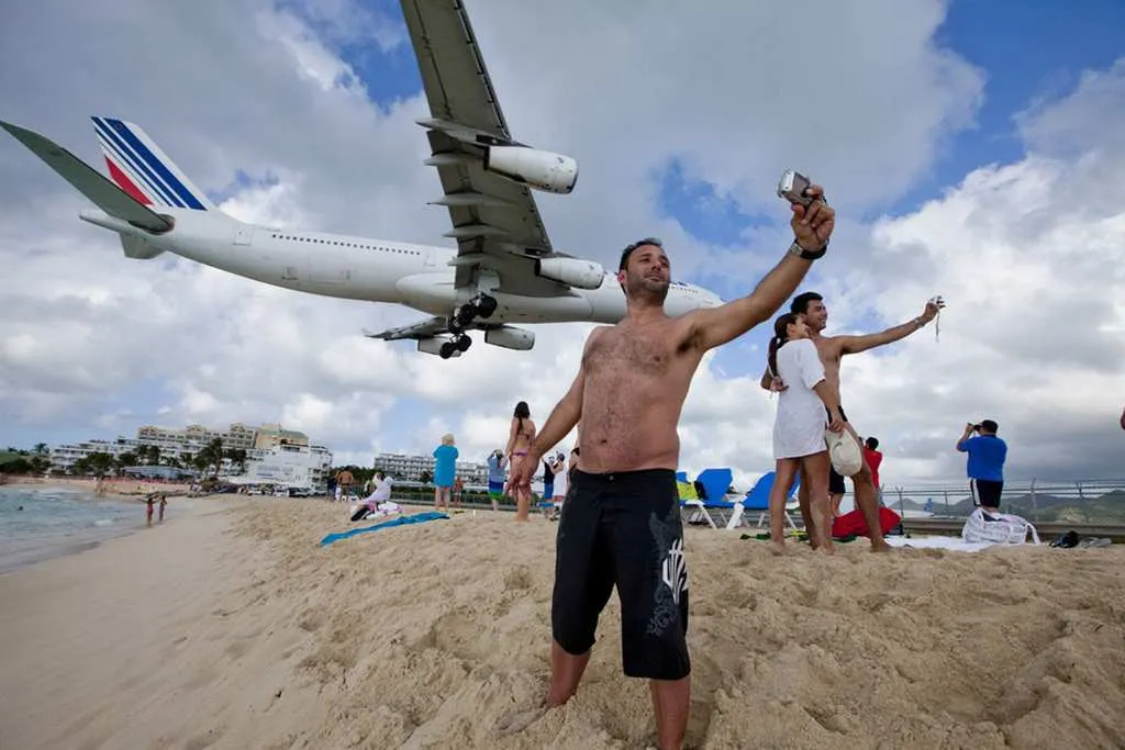 Man taking a selfie with a plane flying over his head