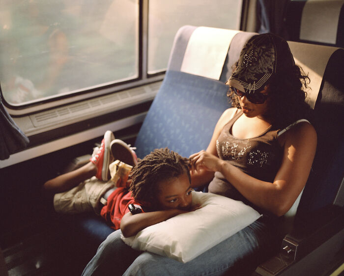 A mother fixing her son's hair on a train