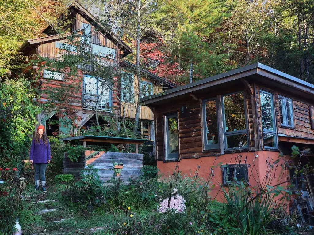 Natalie Bogwalker and the log cabin that she built and expanded on over the years.