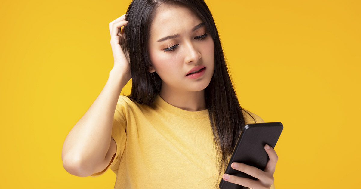 confused woman looking at phone. Yellow background