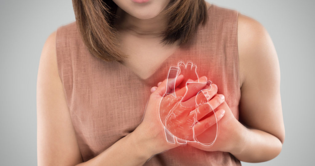The photo of heart is on the woman's body, Severe heartache, Having heart attack or Painful cramps, Heart disease, Pressing on chest with painful expression.
