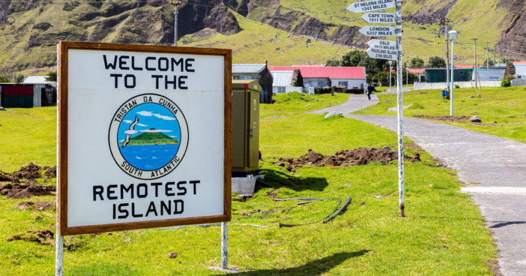 Edinburgh, Tristan da Cunha - Nov 21, 2013: Welcome to the Remotest Island touristic signpost and distance fingerposts to other places in the town centre of Edinburgh of the Seven Seas settlement
