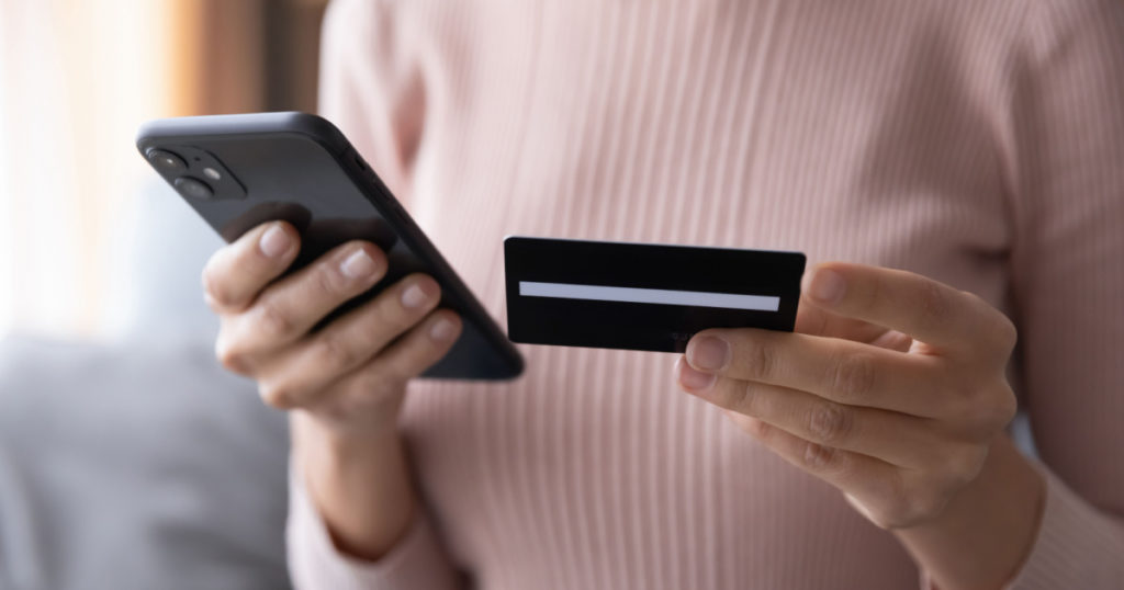 Close up woman paying online by credit card, using smartphone, entering information, young female holding phone, browsing banking service, checking balance, shopping, ordering in internet
