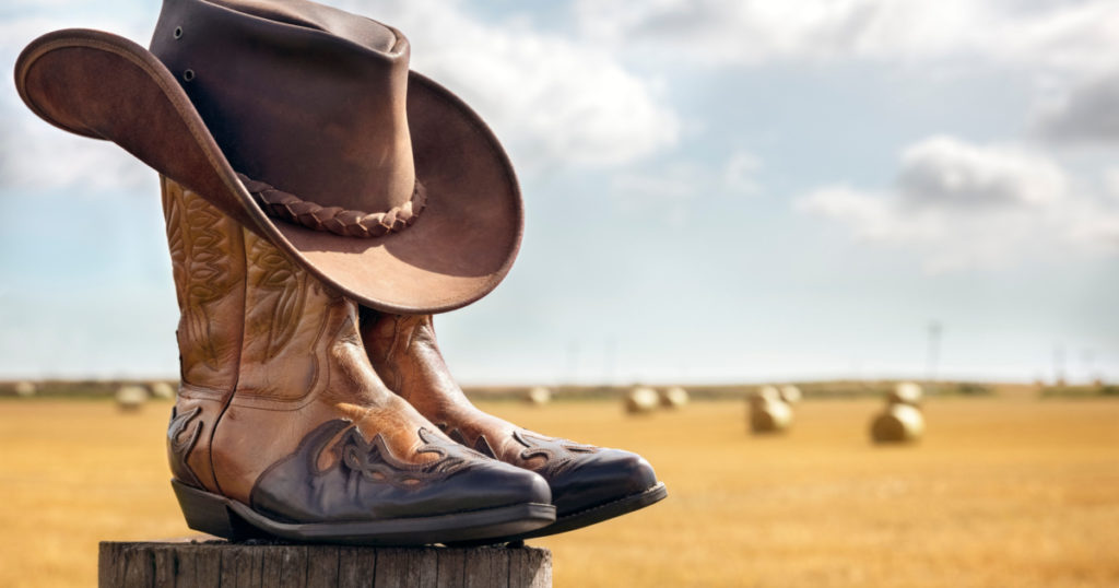 Cowboy boots and hat at ranch, country music festival live concert or line dancing concept
