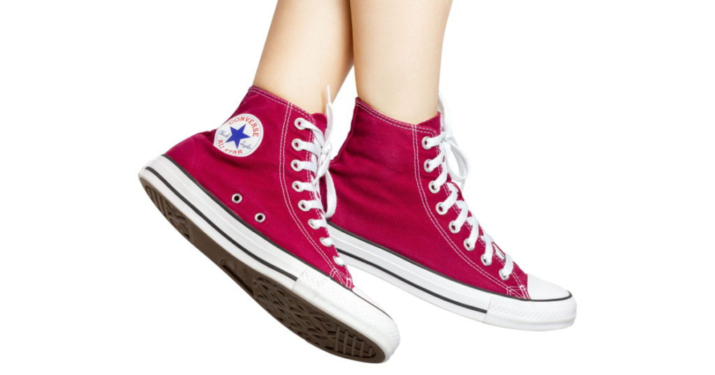 UKRAINE, DNEPR - JUNE 23, 2023: Red Converse All Star sneakers on women's feet. High quality photo
