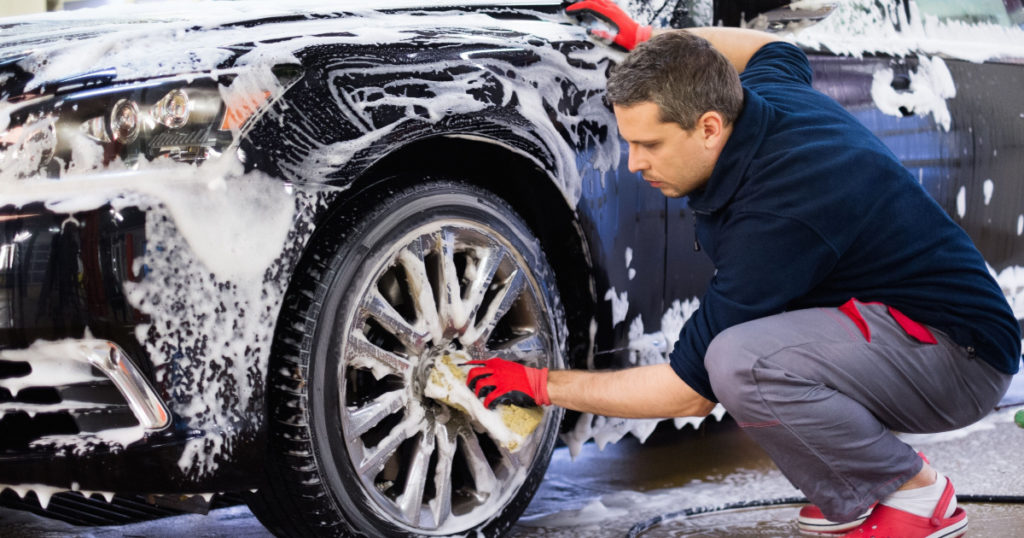 Man worker washing car's alloy wheels on a car wash
