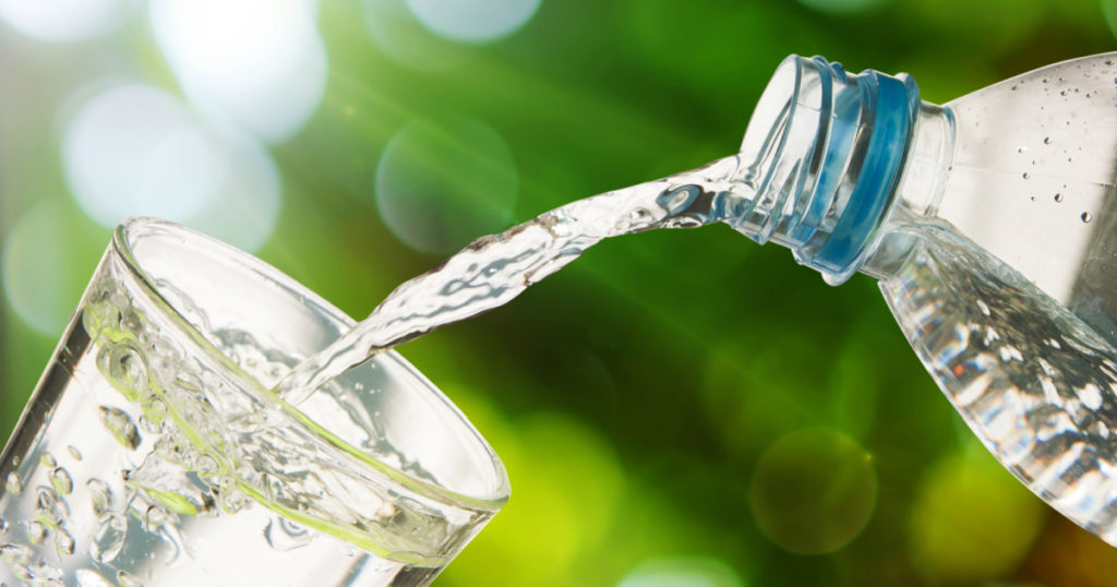 Drinking water is poured from a bottle into a glass
