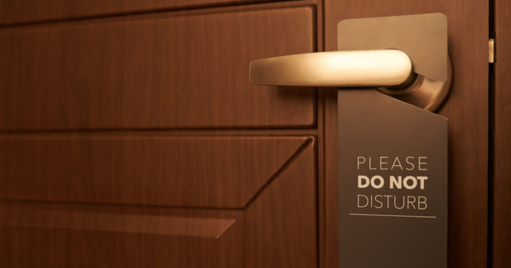 Closed door of hotel room with please do not disturb sign
