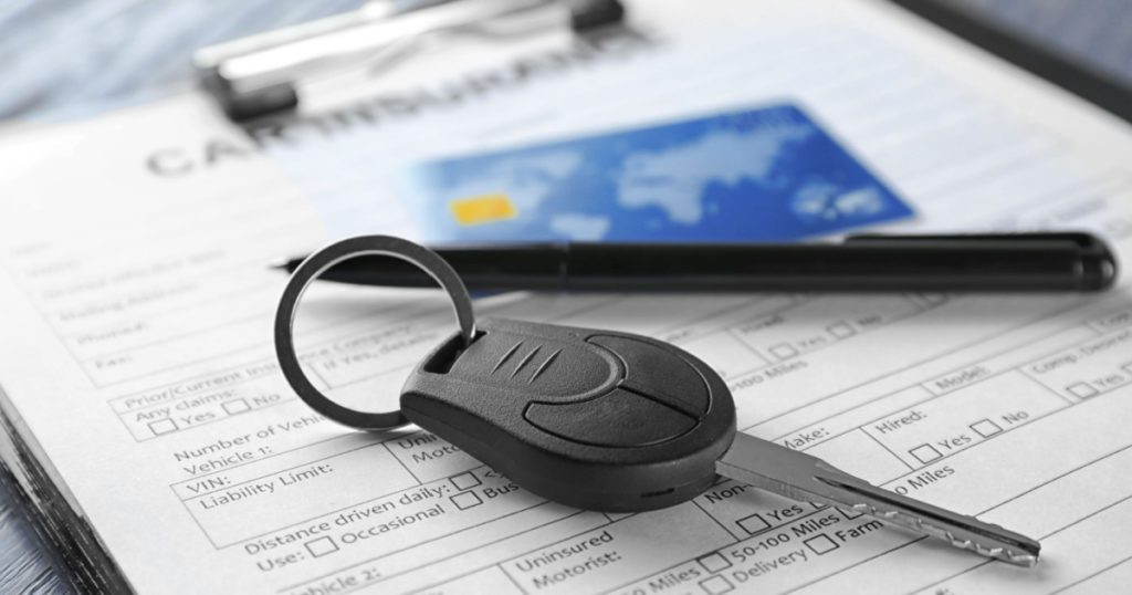 Car insurance form, credit card and key on table
