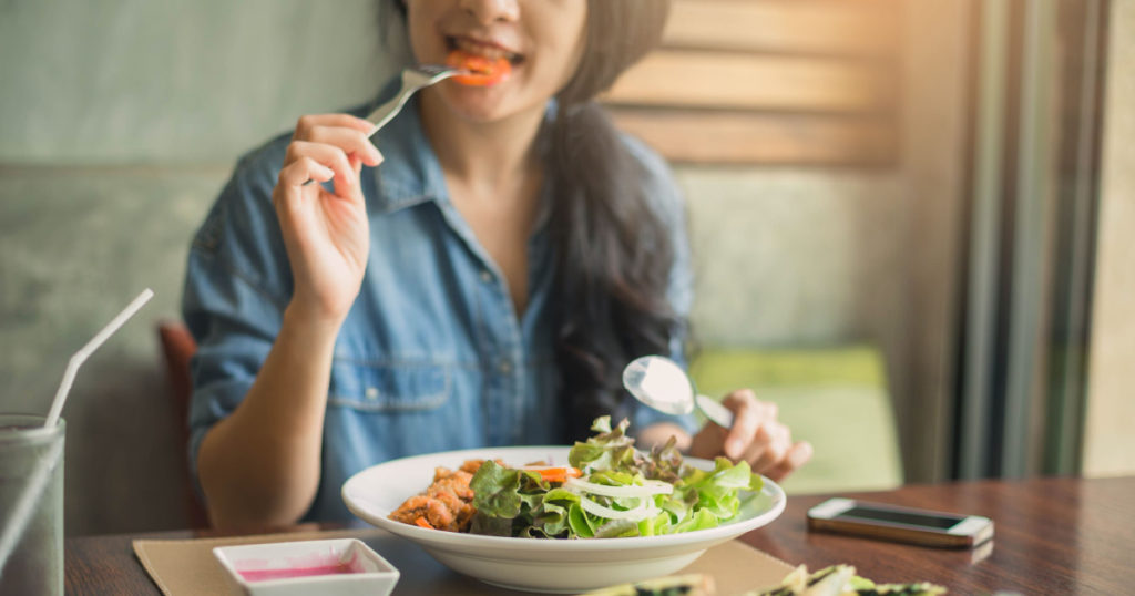 Closeup of a woman eating healthy salad . Beautiful smiling woman eating healthy salad.
