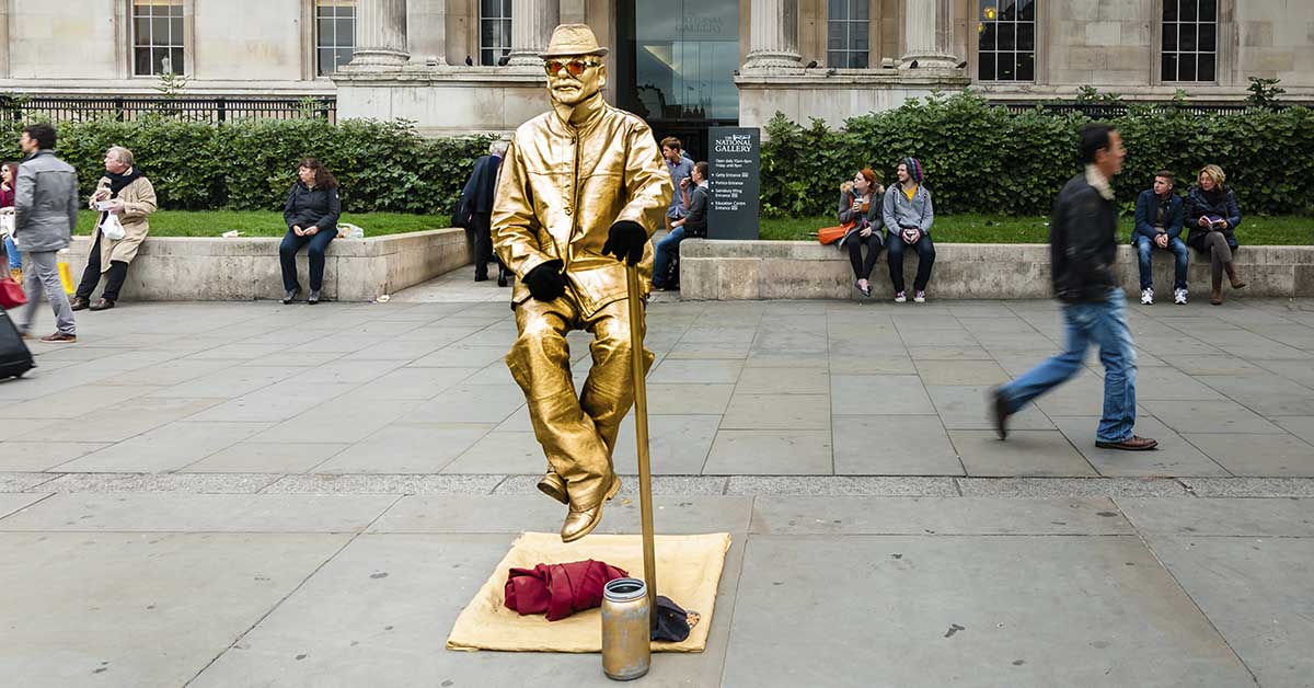 street performer spray painted gold to resemble a statue. He appears to be levatiting