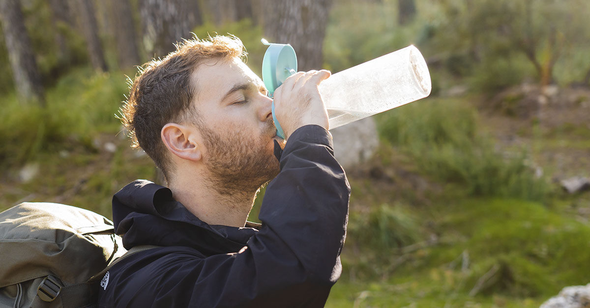 man drinking water on hike