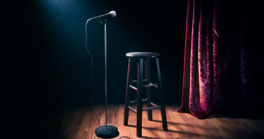 microphone and stool on a stand up comedy stage with reflectors ray, high contrast image
