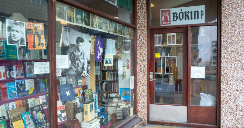 Reykjavik, Iceland - Apr 28 2019: Icelandic second hand bookstore with old books and paperbacks, the picture of Elvis Presley and Paul Newman behind the window.
