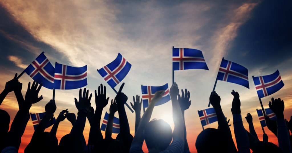 Group of People Waving Icelandic Flags in Back Lit
