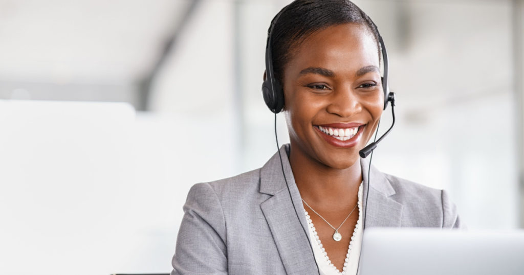 Smiling african american customer care representative working with headset in office. Black woman telemarketing agent working in call center. Call center agent with headset makinga video call.
