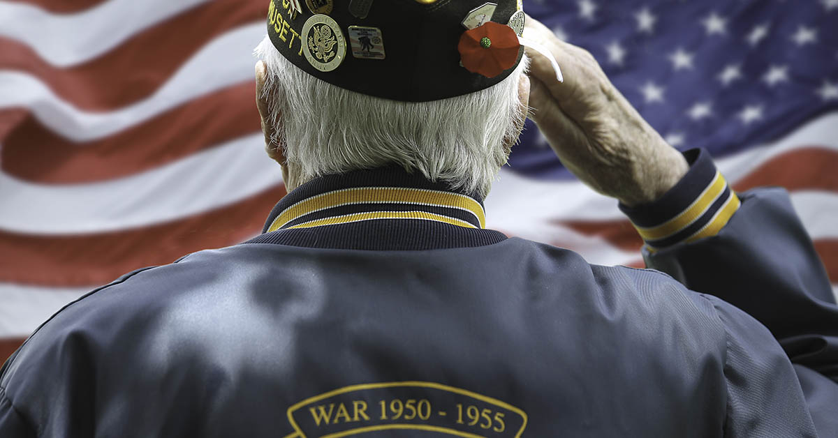 elderly veteran saluting to an american flag.