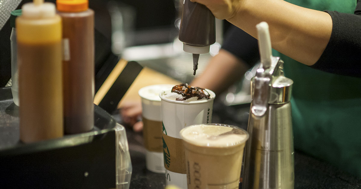 Starbucks barista using various ingredients to make specialty coffees
