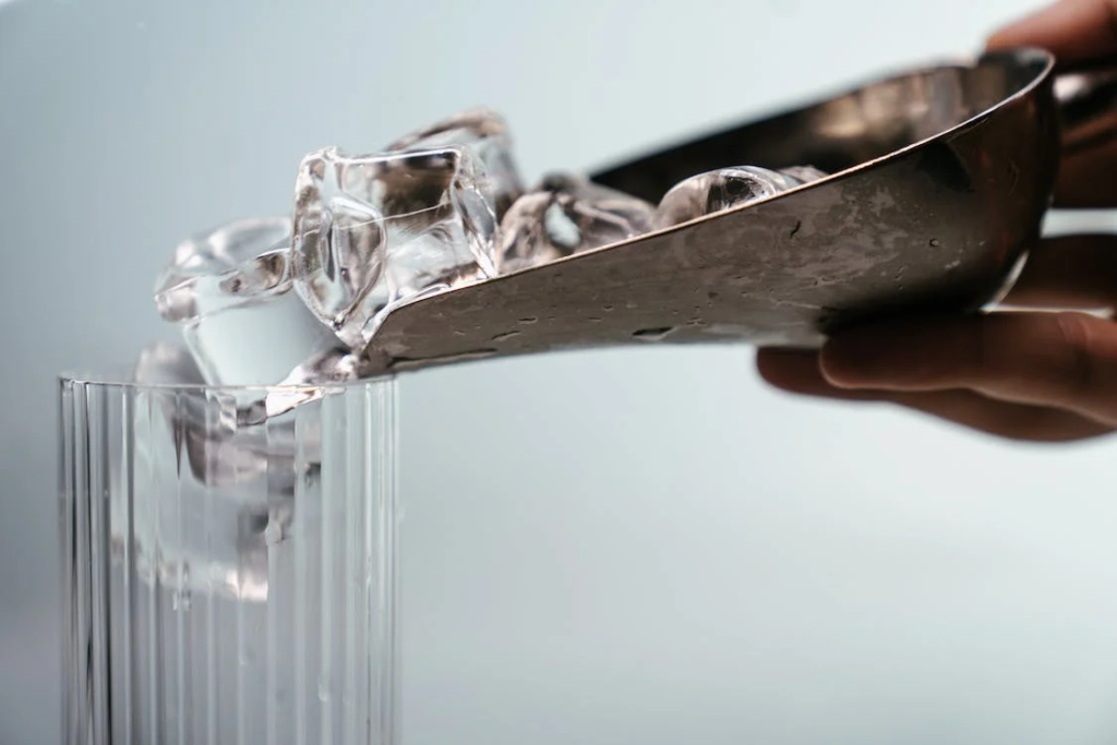 person decanting ice cubes into glass
