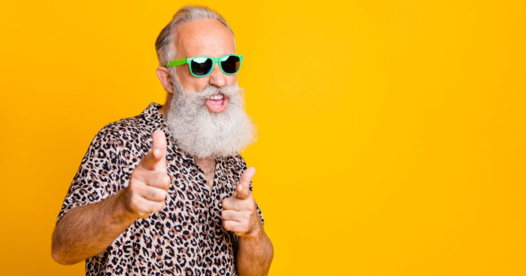 Hey you! Portrait of funky old bearded man in eyeglasses eyewear feel cool crazy point at you wearing leopard shirt isolated over yellow background