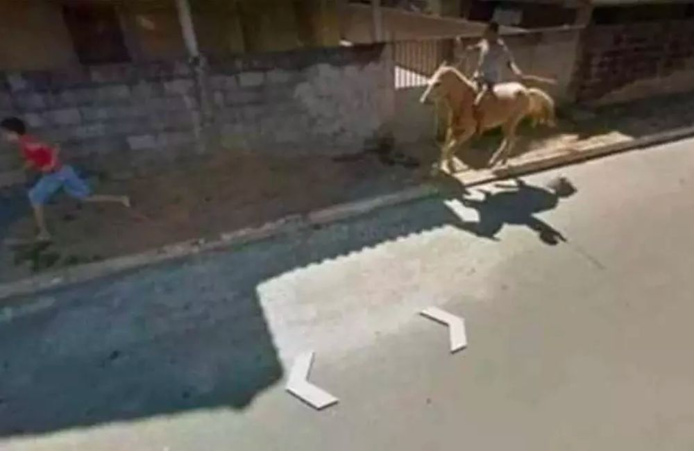 A boy being chased by another on a horse isn't something you see every day, but maybe in a place where horses on sidewalks are normal.